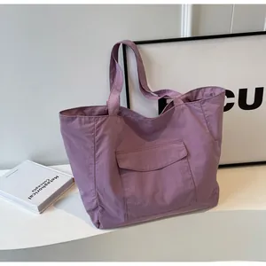 Detail of purple nylon tote bag featuring front flap pocket on a stylish white setup