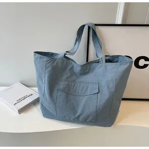 Close-up of light blue nylon tote bag with functional front flap pocket and woven handle
