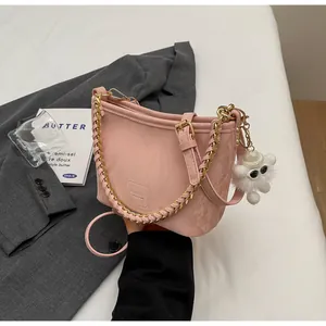 Detail van roze bucket bag met gouden ketting en witte monster pluche hanger