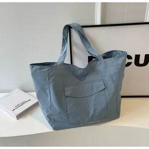 Detailed view of light blue nylon tote bag with large front flap pocket and crinkled texture