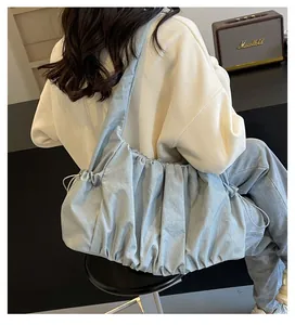 Detailed side view of light blue pleated hobo bag with wide shoulder strap on a model