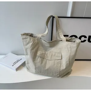 Detail of beige nylon tote bag with front flap pocket and soft wrinkled texture