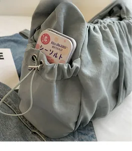 Close-up of light blue pleated handbag showing adjustable drawstring and spacious interior
