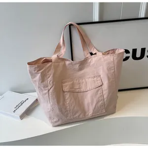 Detail of light pink nylon tote bag with pleated texture and front flap pocket design