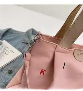 Detailed shot of pink canvas tote with vibrant K embroidery and silver hardware