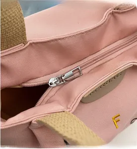 Detail of pink canvas tote showing smooth silver zipper and leather handles with Airbag logo