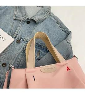 Detail of pink canvas tote showing leather label and colorful embroidered letters