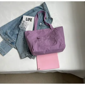 Detail of purple nylon tote bag featuring front flap pocket and spacious interior capacity