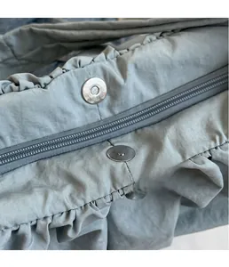 Detail of pleated bag showing metal magnetic buckles and secure zipper closure
