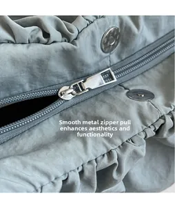 Detail of smooth silver hardware zipper and pleated fabric texture on a crossbody bag