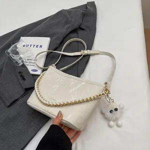 Elegante bucket bag met marmerpatroon in crèmewit, gouden ketting en pluche hanger