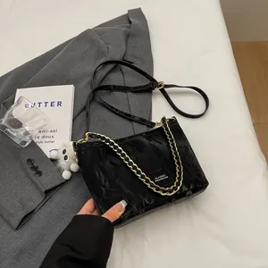 Chique zwarte geplooide emmertas met gouden ketting en witte pluche hanger op een pak