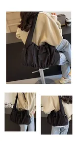 Detail view of large black pleated hobo bag showing nylon texture and drawstring side