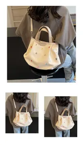 Detail of canvas tote bag showing colorful embroidery and leather logo tag