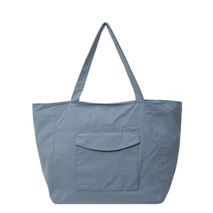 Minimalist blue nylon tote bag with front flap pocket and slim shoulder straps