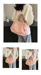 Pink canvas tote bag detail showing colorful letter embroidery and leather logo tag
