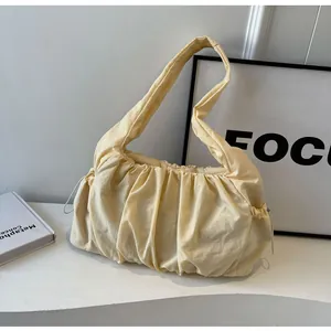 Detail of light yellow ruched fabric and drawstring design on a minimalist shoulder bag