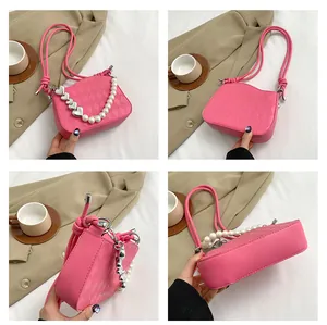 Détail du sac bandoulière rose fuchsia avec texture matelassée et chaîne perle et cœur