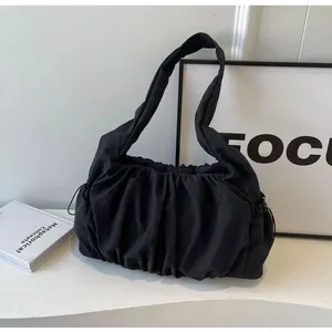 Detail of black pleated cloud shoulder bag showing ruched texture and wide strap design
