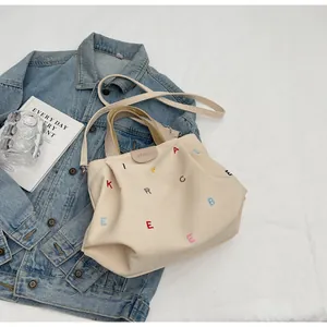 Detail of canvas tote bag with colorful letter embroidery and brand logo patch