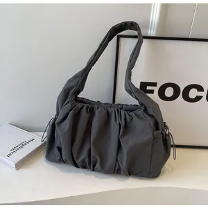 Detailed view of dark grey pleated shoulder bag with drawstrings and cloud-like texture