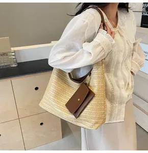 Detail of straw woven tote bag featuring brown leather trim and a magnetic clip accessory