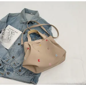 Detail of colorful embroidered letters and brand patch on khaki canvas tote bag