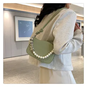 Détail du sac demi-lune vert clair avec texture matelassée, perles et chaîne cœur