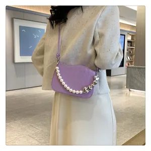 Détail du sac bandoulière violet matelassé avec chaîne perles porté sur veste en tweed
