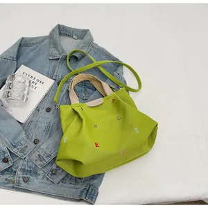 Close-up of vibrant green canvas tote with colorful embroidery and leather label