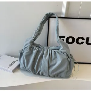 Close-up of light blue pleated cloud bag with drawstring detail and thick strap