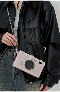 Dettaglio della borsa a tracolla rosa a forma di fotocamera con strass e catena