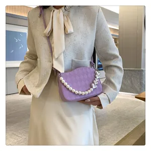 Détail du sac bandoulière matelassé violet avec chaîne en perles et breloques cœur