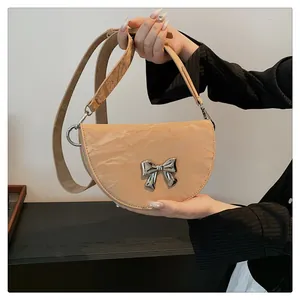 Détail du sac demi-lune beige avec texture plissée et accessoire de nœud argenté