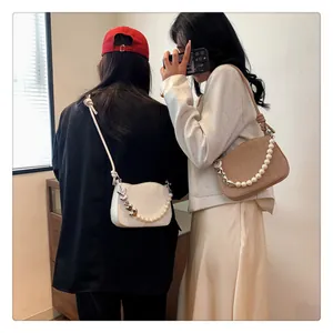 Détail de sacs tressés avec perles et chaînes de cœur en beige et blanc