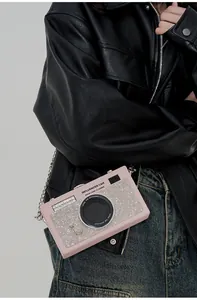 Dettaglio borsa a tracolla a forma di fotocamera rosa con strass e catena argentata