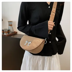 Gros plan du sac besace beige avec nœud en métal argenté et cuir à texture marbrée