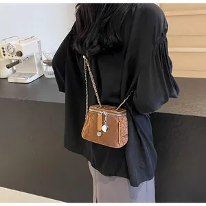 Gros plan du sac bandoulière marron avec pendentif fleur et texture plissée élégante