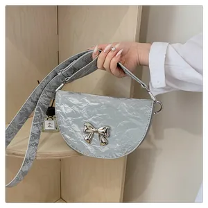 Détail du sac selle argenté avec texture métallique plissée et décoration de nœud