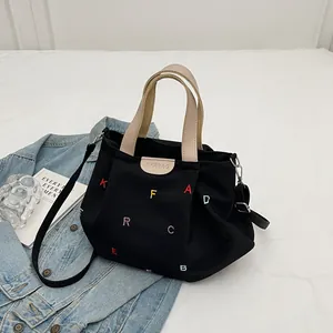 Black canvas tote bag with colorful embroidered letters and crossbody shoulder strap