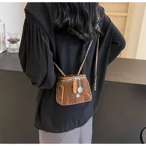 Détail du sac bandoulière marron plissé avec breloque fleur argentée et bandoulière chaîne