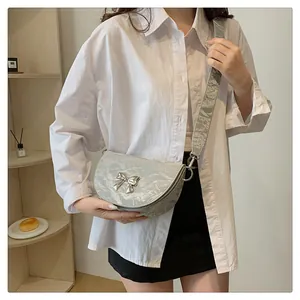 Détail du sac demi-lune plissé bleu clair avec nœud argenté porté par un mannequin