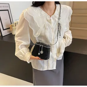 Détail d'un mini sac seau matelassé noir avec chaîne argentée et breloques de fleurs