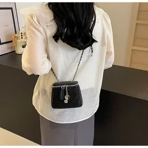 Mini sac vanity noir chic avec bandoulière chaîne argentée porté par un mannequin stylé