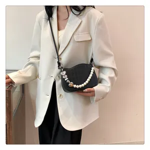 Détail du petit sac bandoulière noir matelassé avec chaîne de perles et breloque cœur argenté
