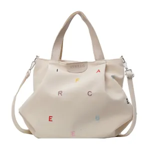 Off-white canvas tote bag with colorful letter embroidery and adjustable shoulder strap