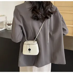 Détail du mini sac seau matelassé blanc avec pendentif camélia et bandoulière chaîne