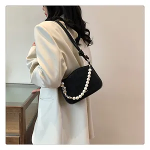 Détail d'un sac bandoulière matelassé noir avec perles et chaîne en métal en cœur