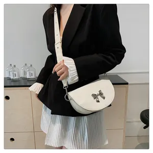 Détail du sac selle blanc en demi-lune avec boucle nœud argentée et bandoulière large