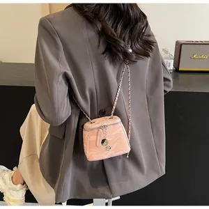 Détail du mini sac boîte rose avec bandoulière chaîne et pendentif fleur de camélia